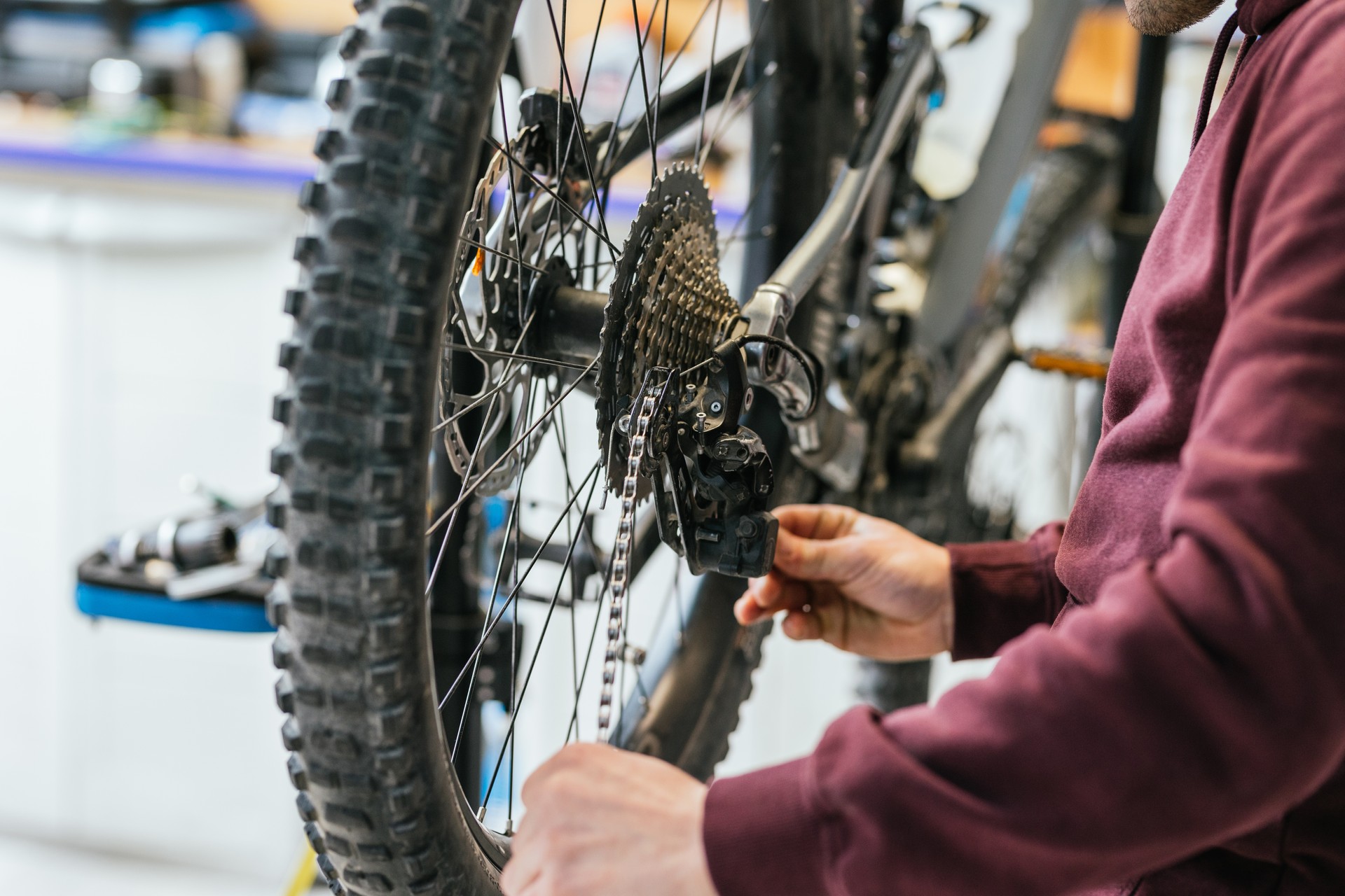 Close-up of the mechanic's hands on the wheel of a mountain bike, with focus centered on the chain and the rear derailleur