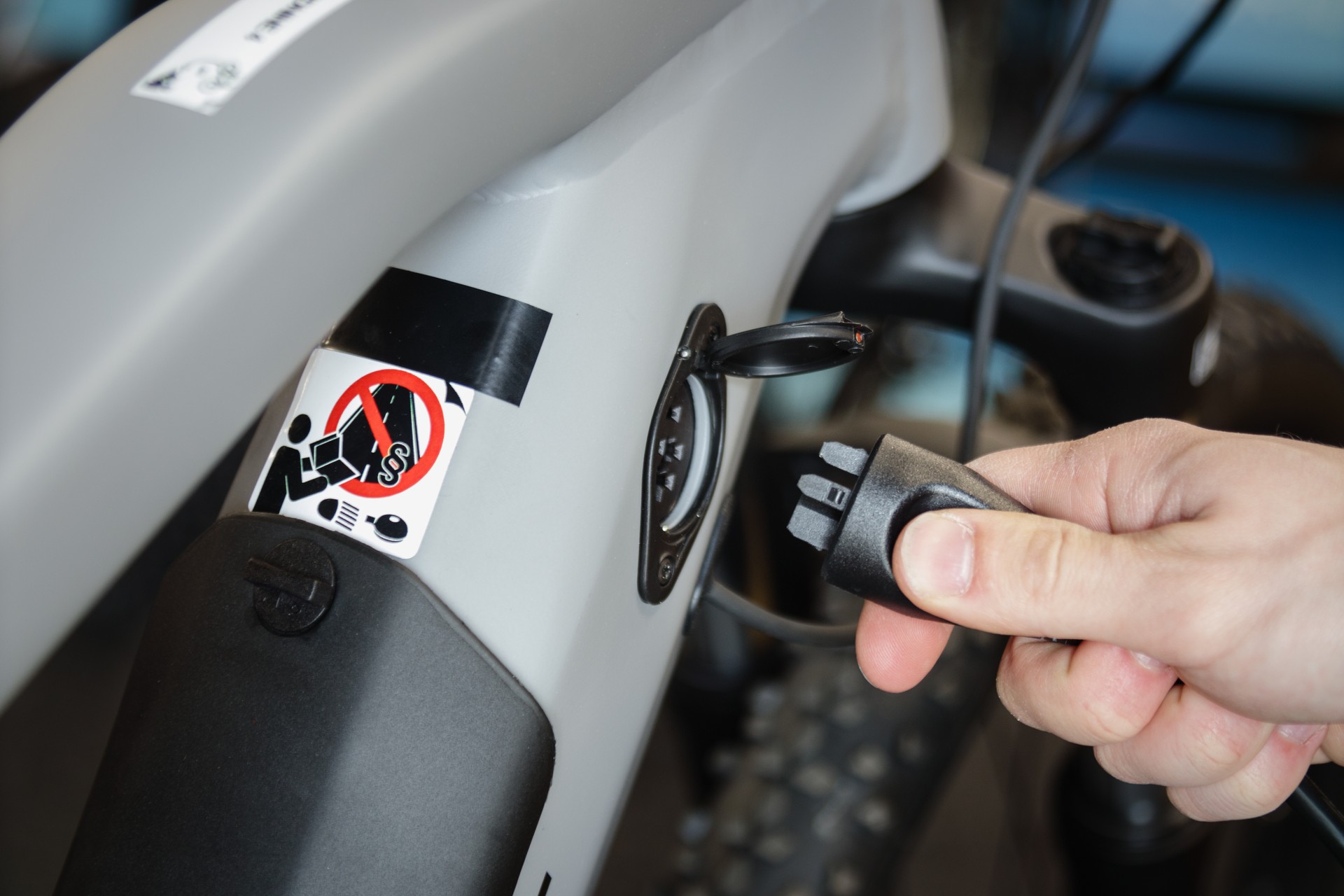 Close up shoto of male hands plugging in charger to an electric bicycle frame